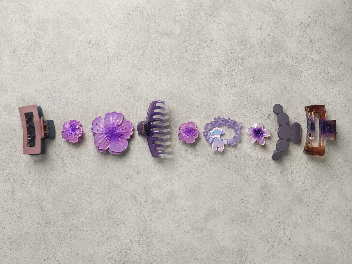 Set of purple hair clips on a gray surface