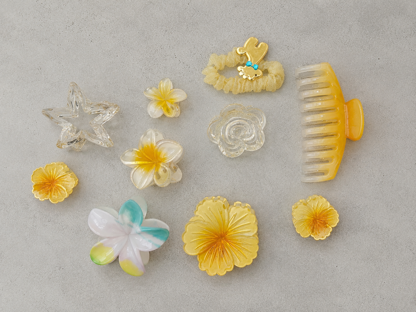 Collection of various hair accessories including flowers and a comb on a gray background