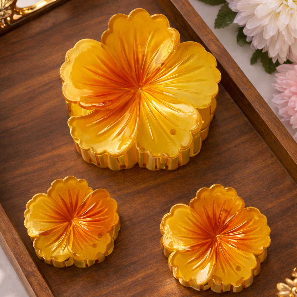 Three yellow floral pastries on a wooden tray with decorative handles, surrounded by flowers.