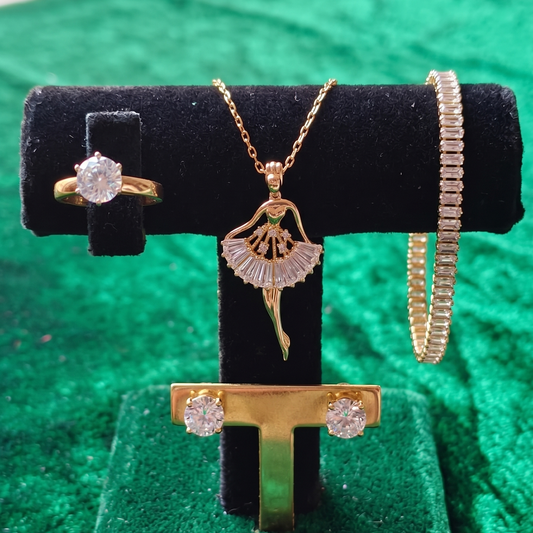 Gold jewelry set including a ring, necklace, and bracelet on a black display stand against a green background.