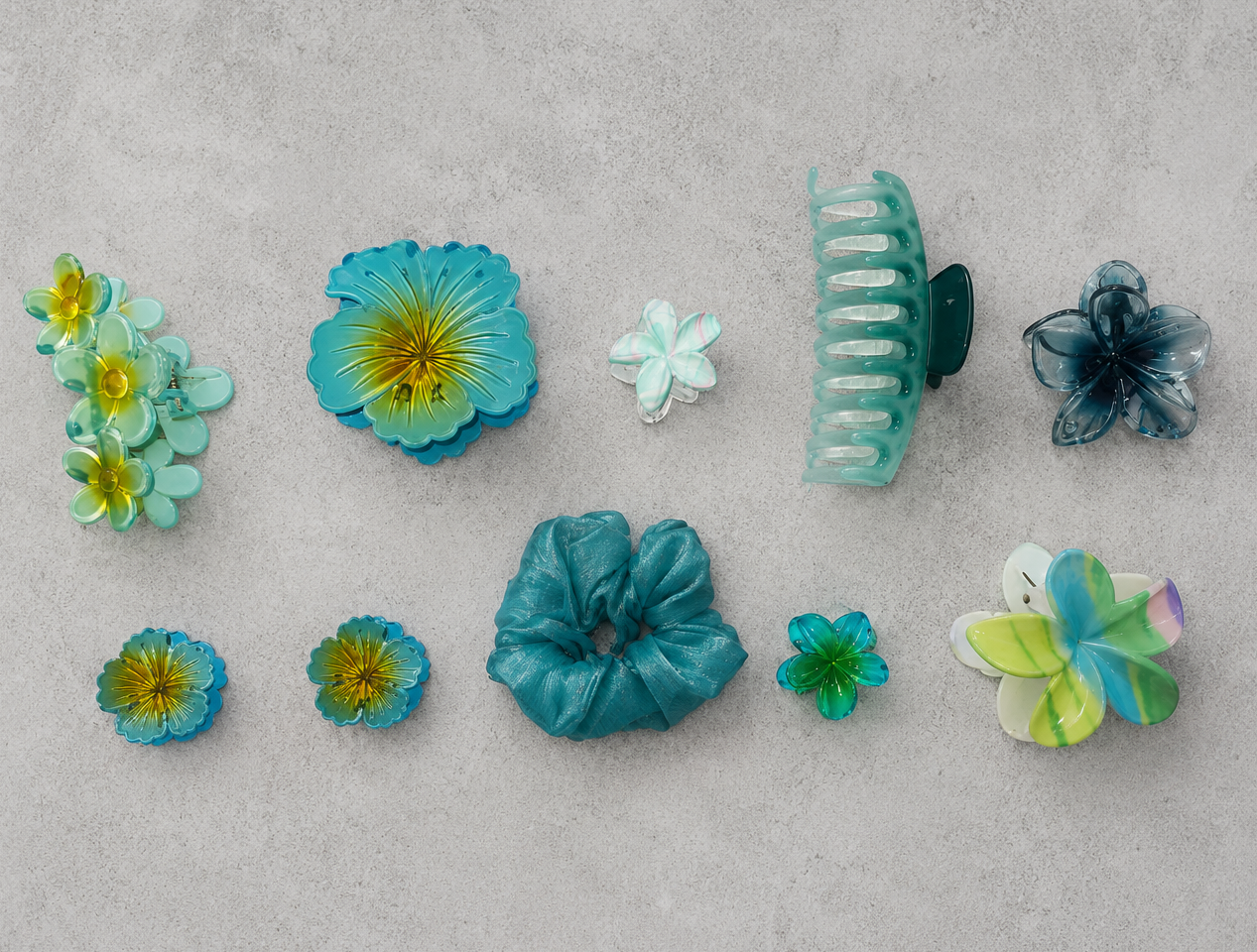 Collection of colorful hair accessories including flowers and scrunchies on a gray surface