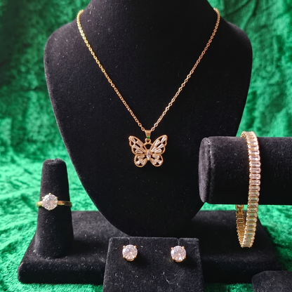 Gold butterfly necklace, ring, and earrings on a black mannequin bust against a green textured background.