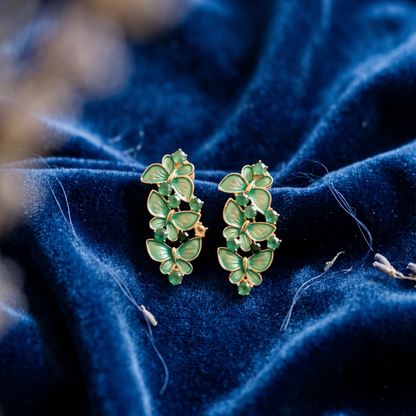 Green leaf-shaped earrings on a blue fabric background
