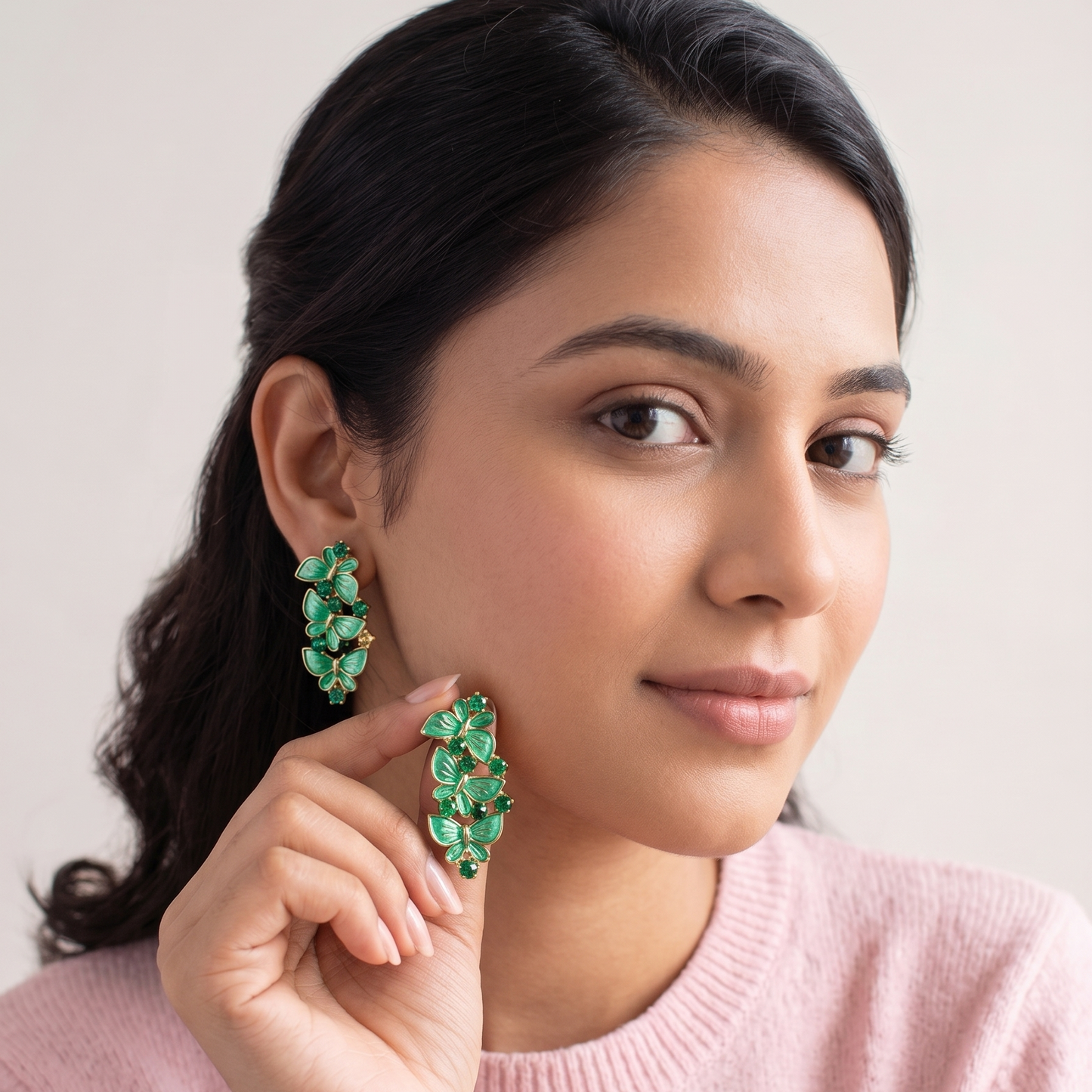 Woman wearing green floral earrings with a plain background