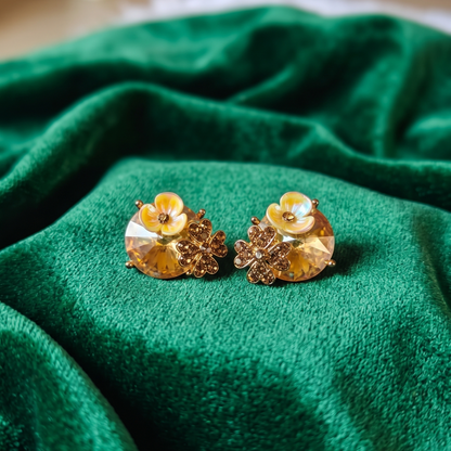 Gold floral earrings on a green fabric surface