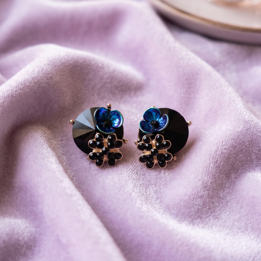 Pair of earrings with blue gemstones on a soft pink fabric background