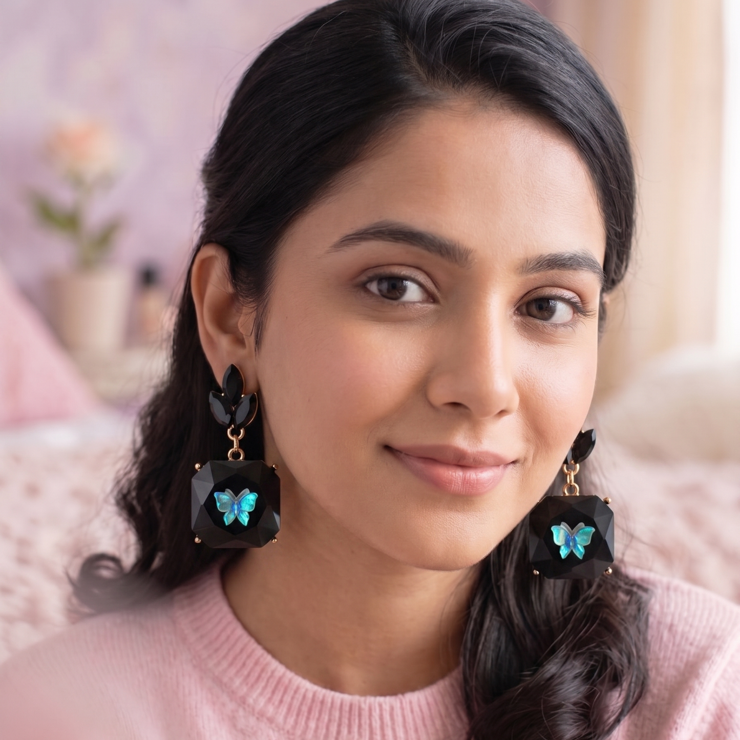 Woman wearing earrings with a pink sweater in a softly blurred indoor setting