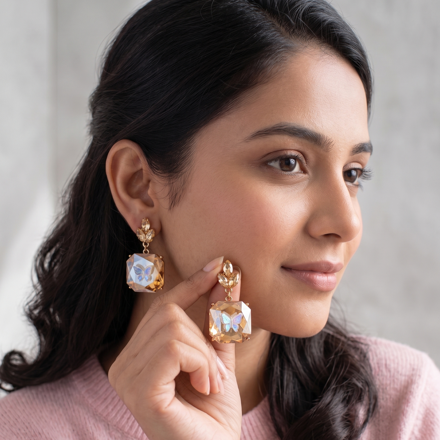 Woman wearing sparkling earrings, holding one with a neutral background