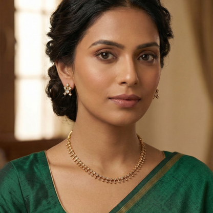 Woman wearing a green saree with gold plated jewelry against a neutral background