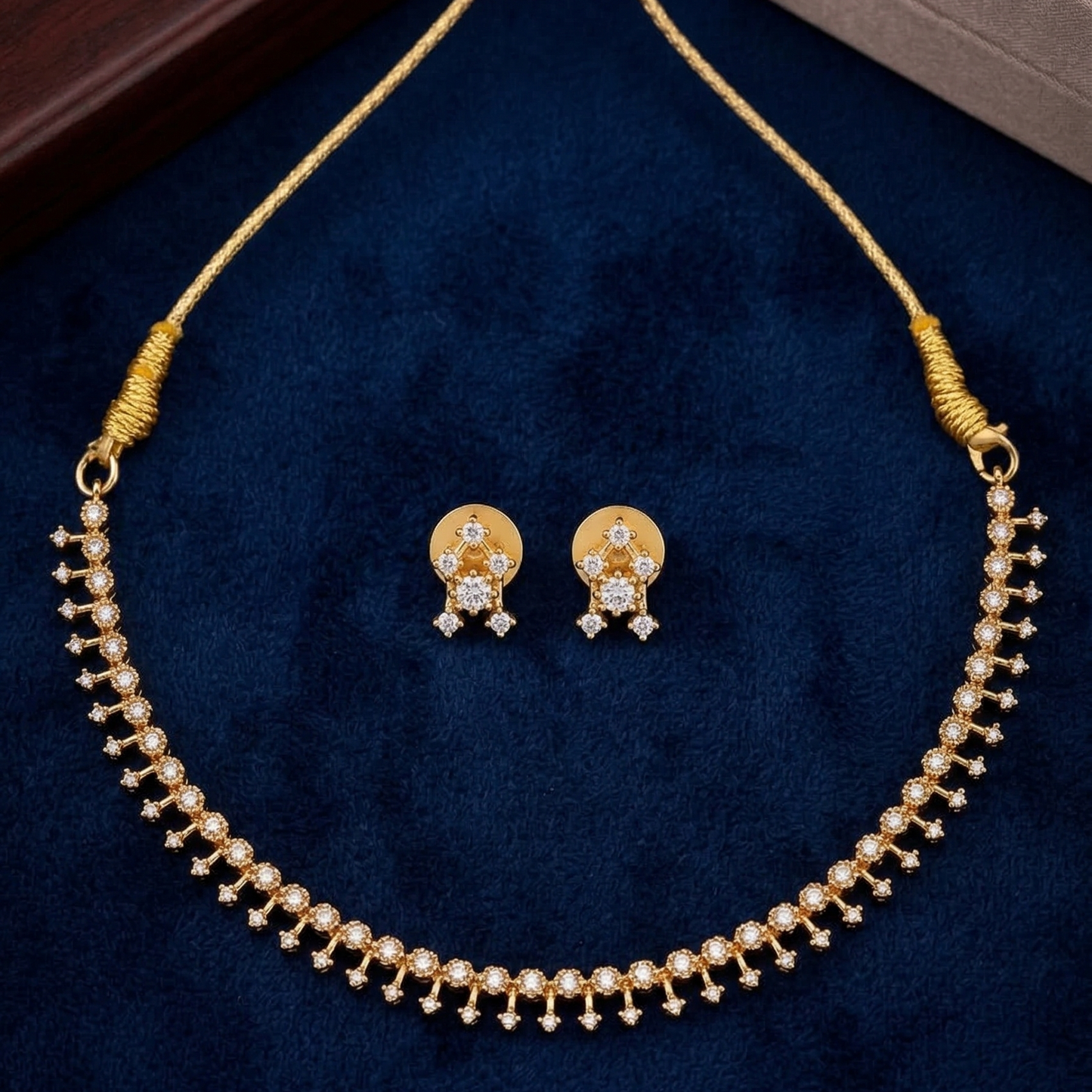 Gold plated necklace and earrings set on a blue velvet background