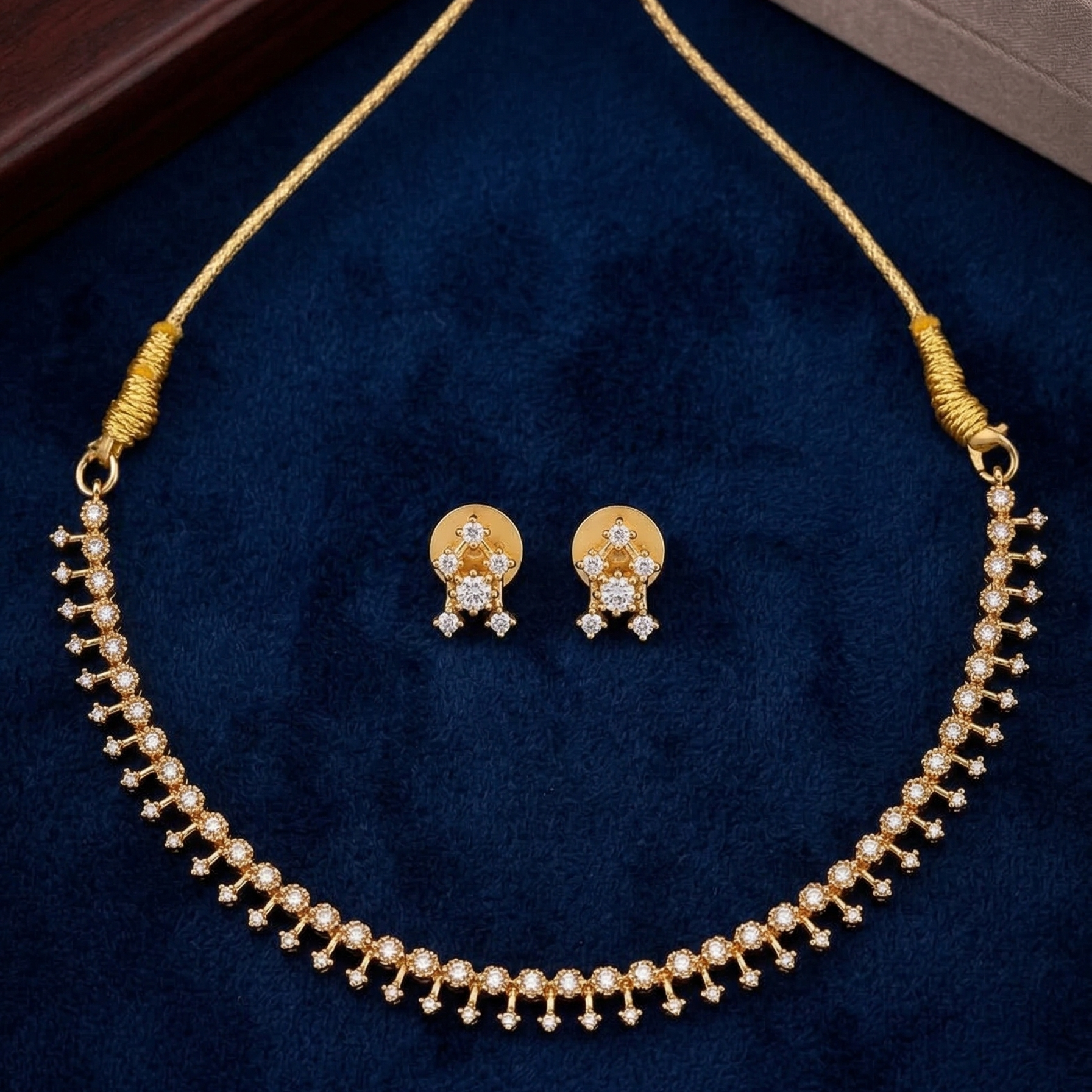 Gold plated necklace and earrings set on a blue velvet background