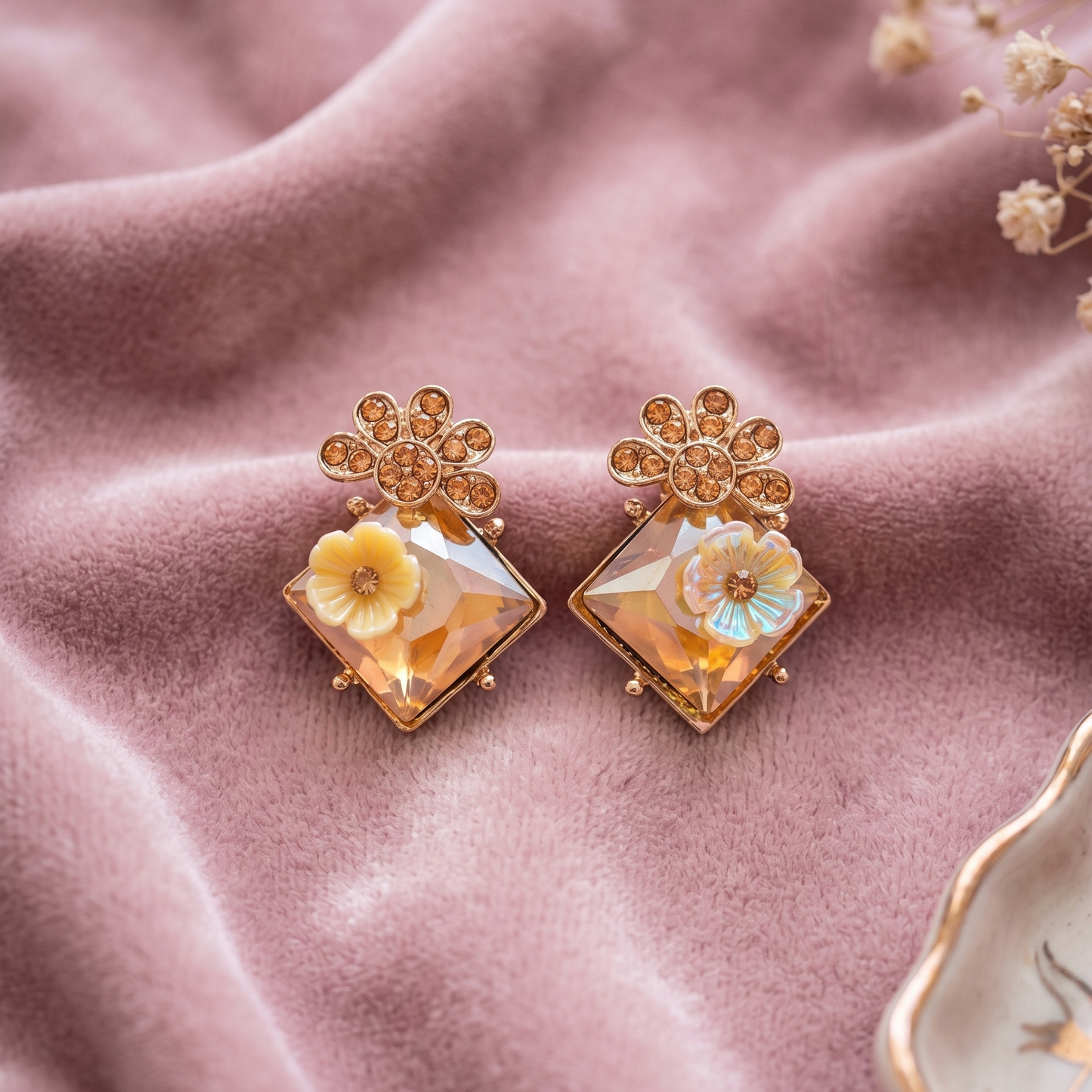 Pair of floral earrings on a pink fabric background
