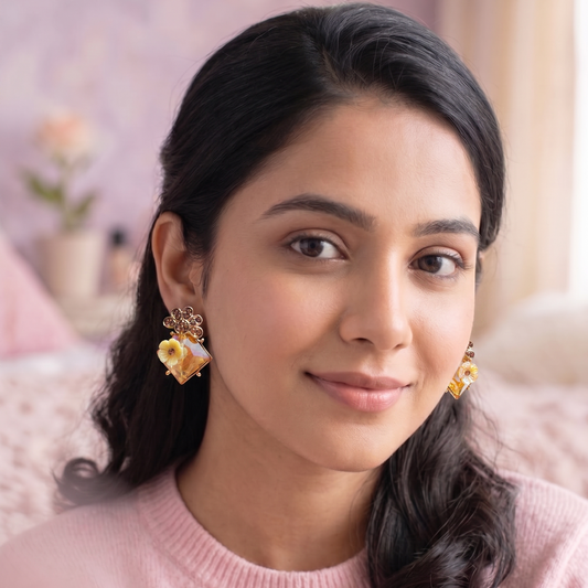 Woman wearing gold earrings with a pink sweater in a soft, blurred indoor setting