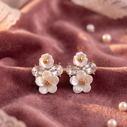 Floral earrings on a textured fabric background with 'Aura Jewels' branding.