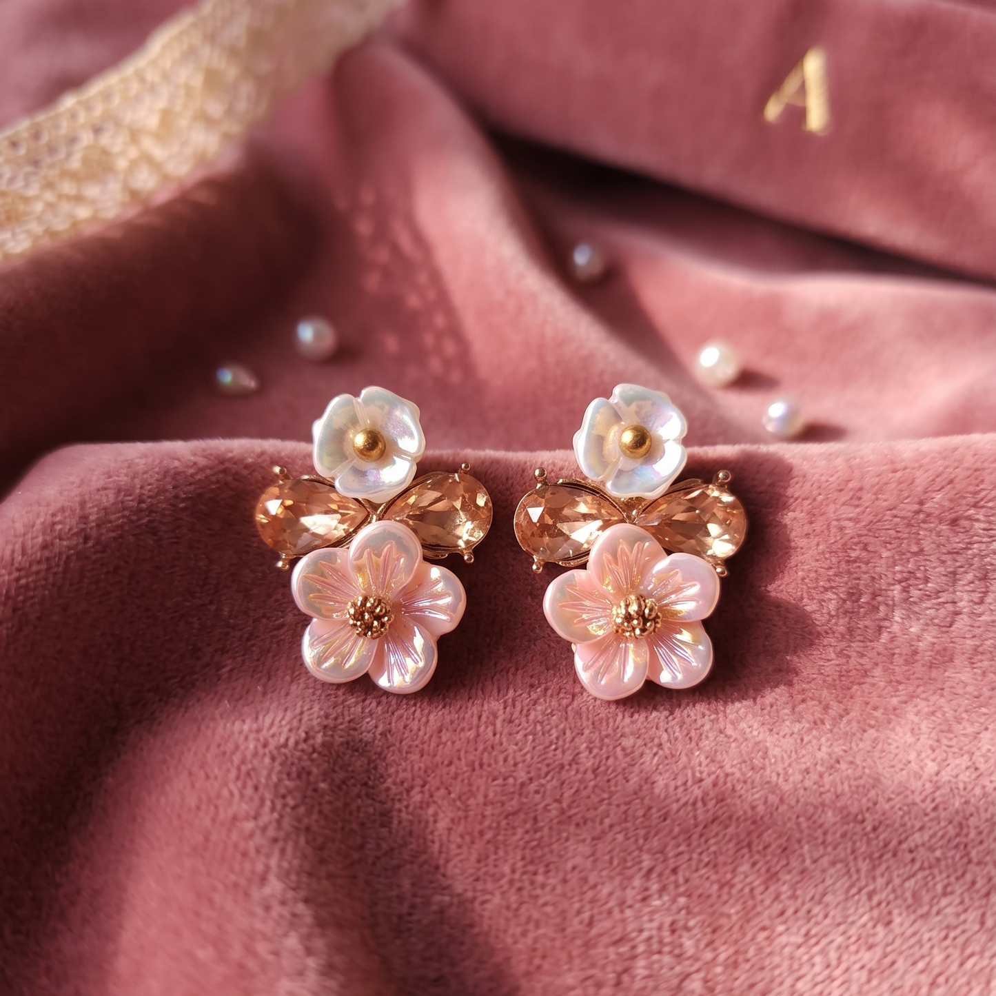 Floral earrings on a pink fabric background