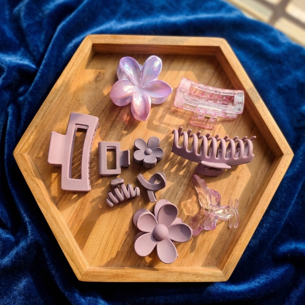 Set of purple hair clips on a wooden hexagonal tray with a blue fabric background