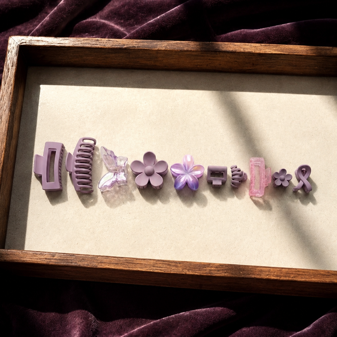 Set of purple and pink hair clips on a wooden tray with a purple fabric background