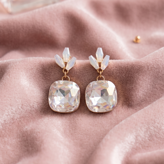 Pair of earrings with large crystals on a pink fabric background