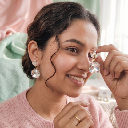 Woman wearing diamond earrings in a soft, blurred indoor setting
