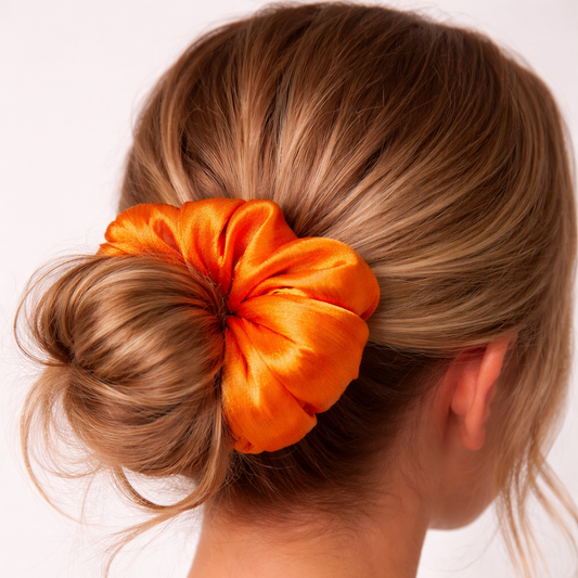 Orange scrunchie in a bun on a person's head with a white background