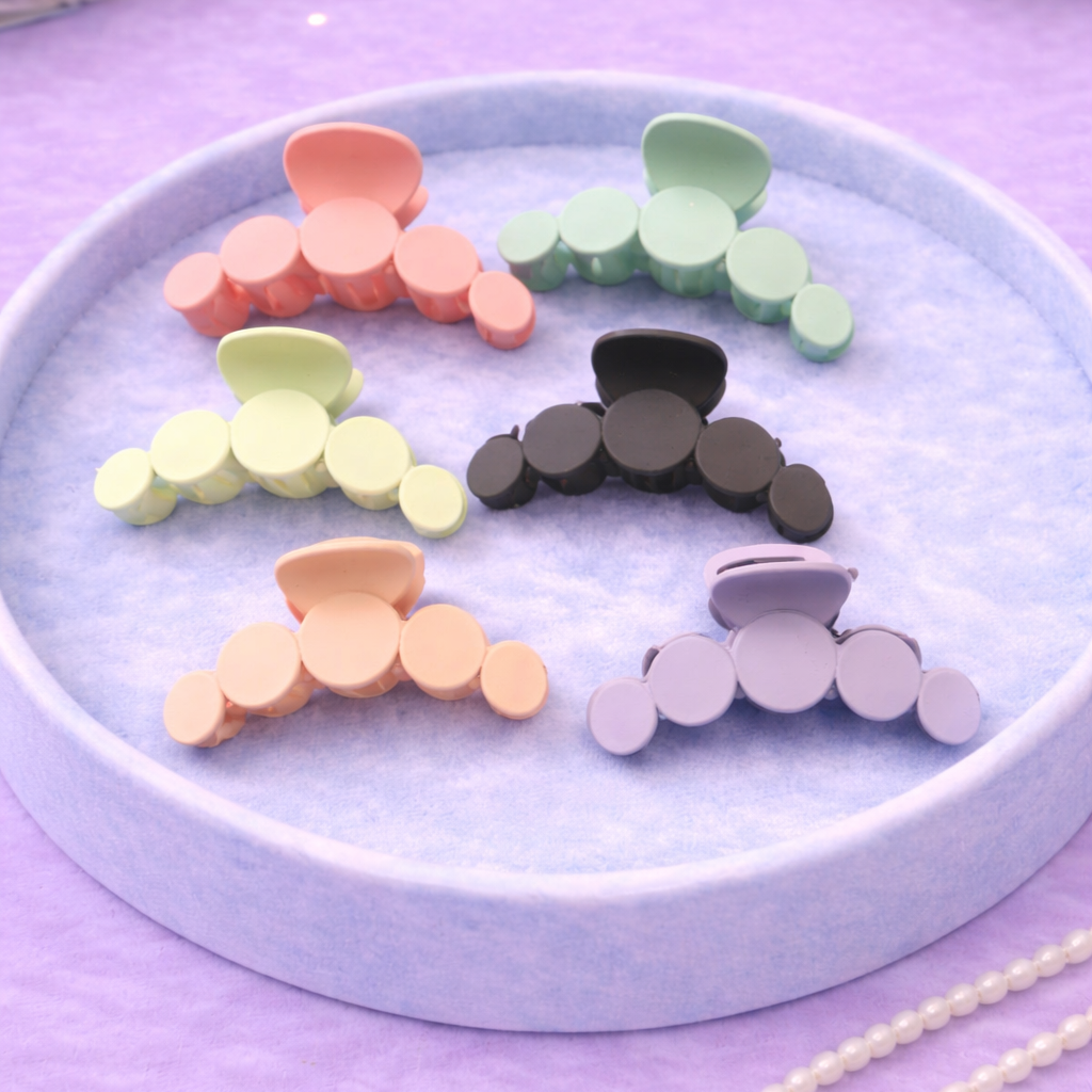 Colorful hair clips on a round blue tray with a purple background