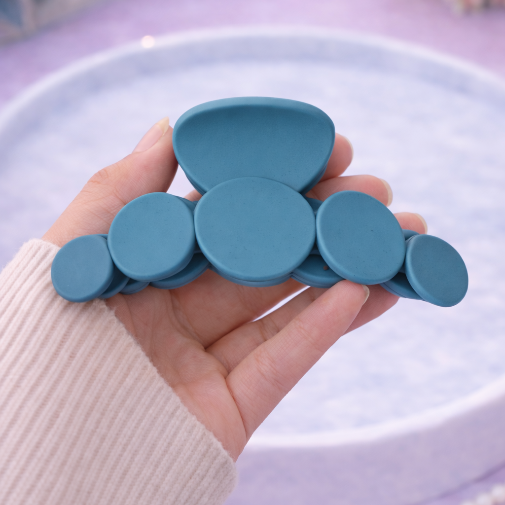 Hand holding a set of blue silicone teether against a light blue background