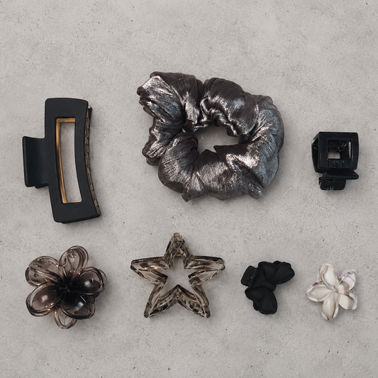 Collection of hair accessories including a scrunchie, clips, and flowers on a gray surface.