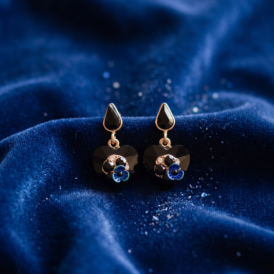 Gold earrings with blue stones on a blue fabric background