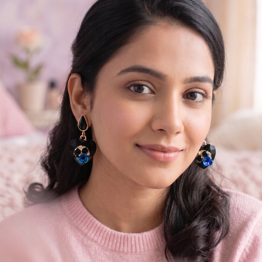 Woman wearing earrings with a pink sweater in a softly blurred indoor setting
