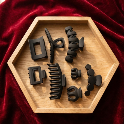 Set of black hair styling tools on a wooden hexagonal tray with a red fabric background