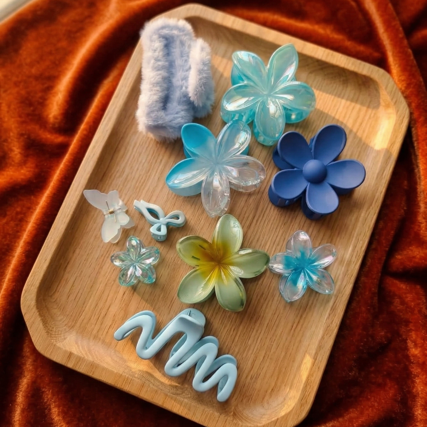 Wooden tray with floral and butterfly-shaped bath bombs on a textured orange fabric background