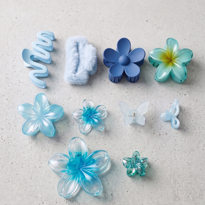 Collection of blue and clear plastic hair accessories on a light gray surface