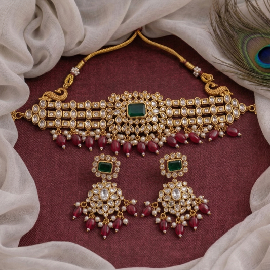 Gold necklace with red stones and green gemstones on a maroon fabric background