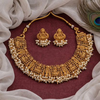 Gold necklace and earrings with pearls on a maroon fabric background