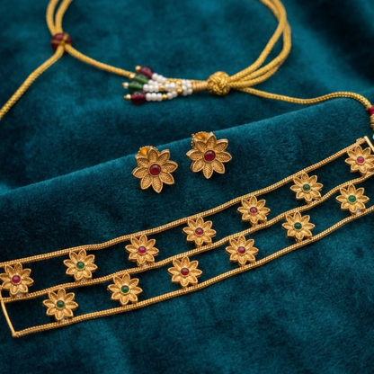 Gold jewelry set with floral designs on a teal fabric background