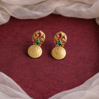Gold earrings with gemstones on a red fabric background