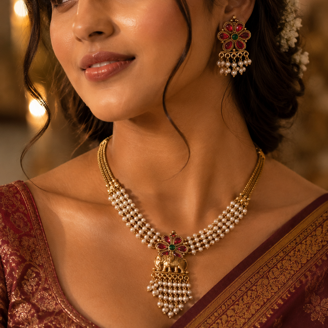 Woman wearing traditional jewelry including a necklace and earrings, with a blurred background.