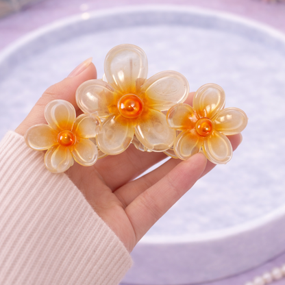 Hand holding a floral hair clip with a blurred background