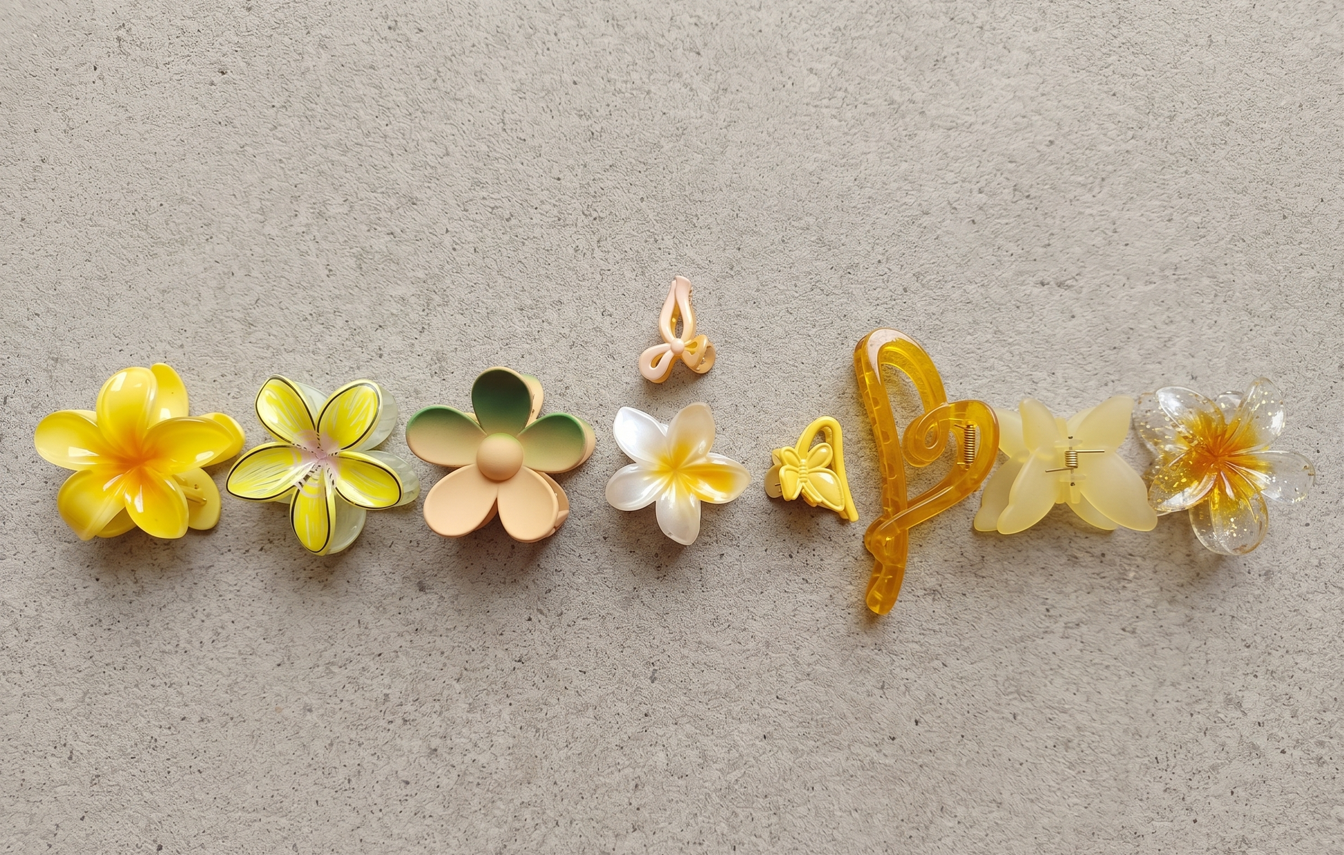 Set of colorful flower-shaped hair clips on a textured beige background