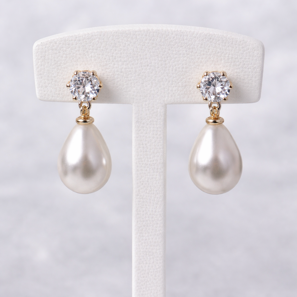 Pearl earrings with crystal tops on a white stand against a light gray background